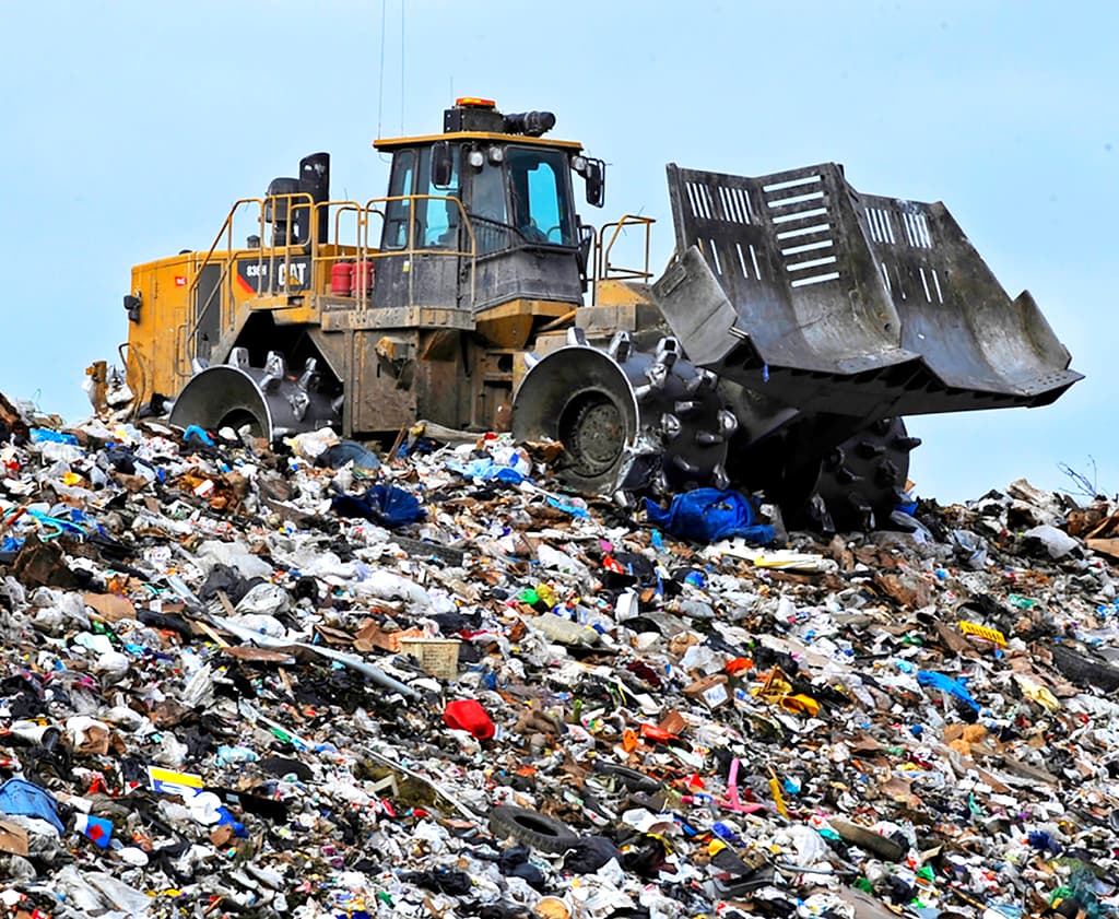 A compactor working across a landfill of spread waste